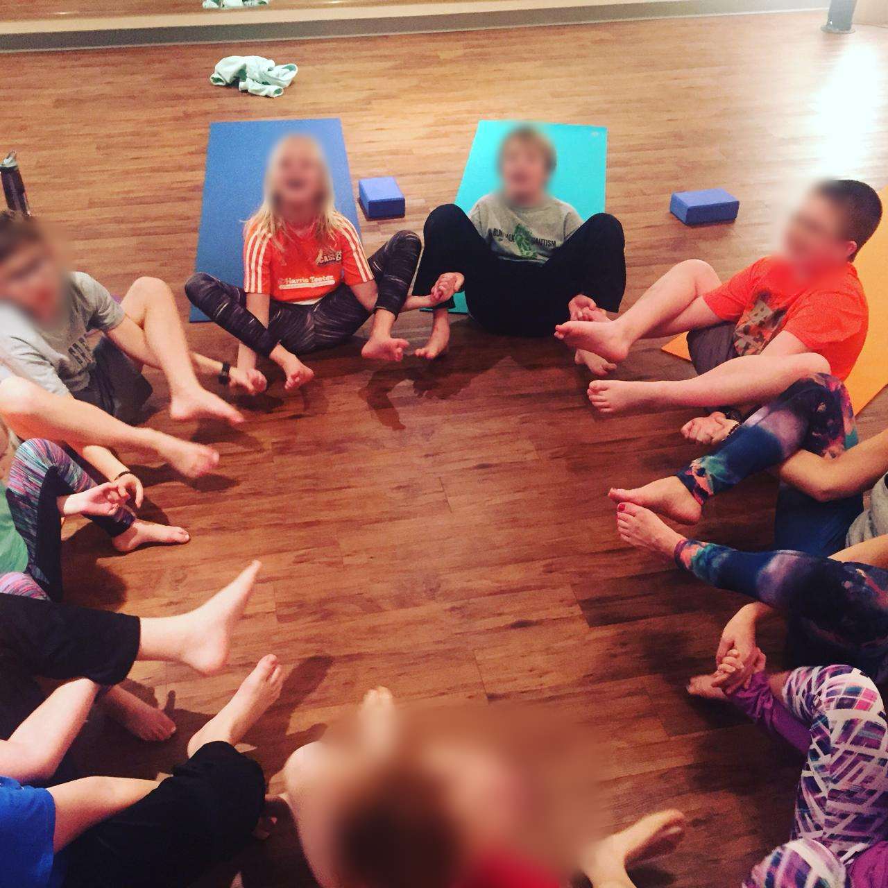 Campers in a joyful circle on the studio floor — community at the heart of camp
